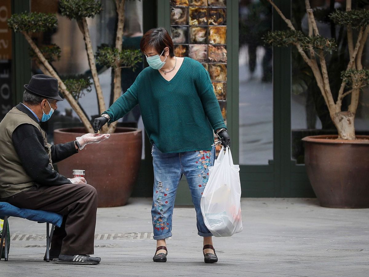 Foto: Una mujer da dinero a una persona sin hogar. (EFE/José Manuel Vidal)