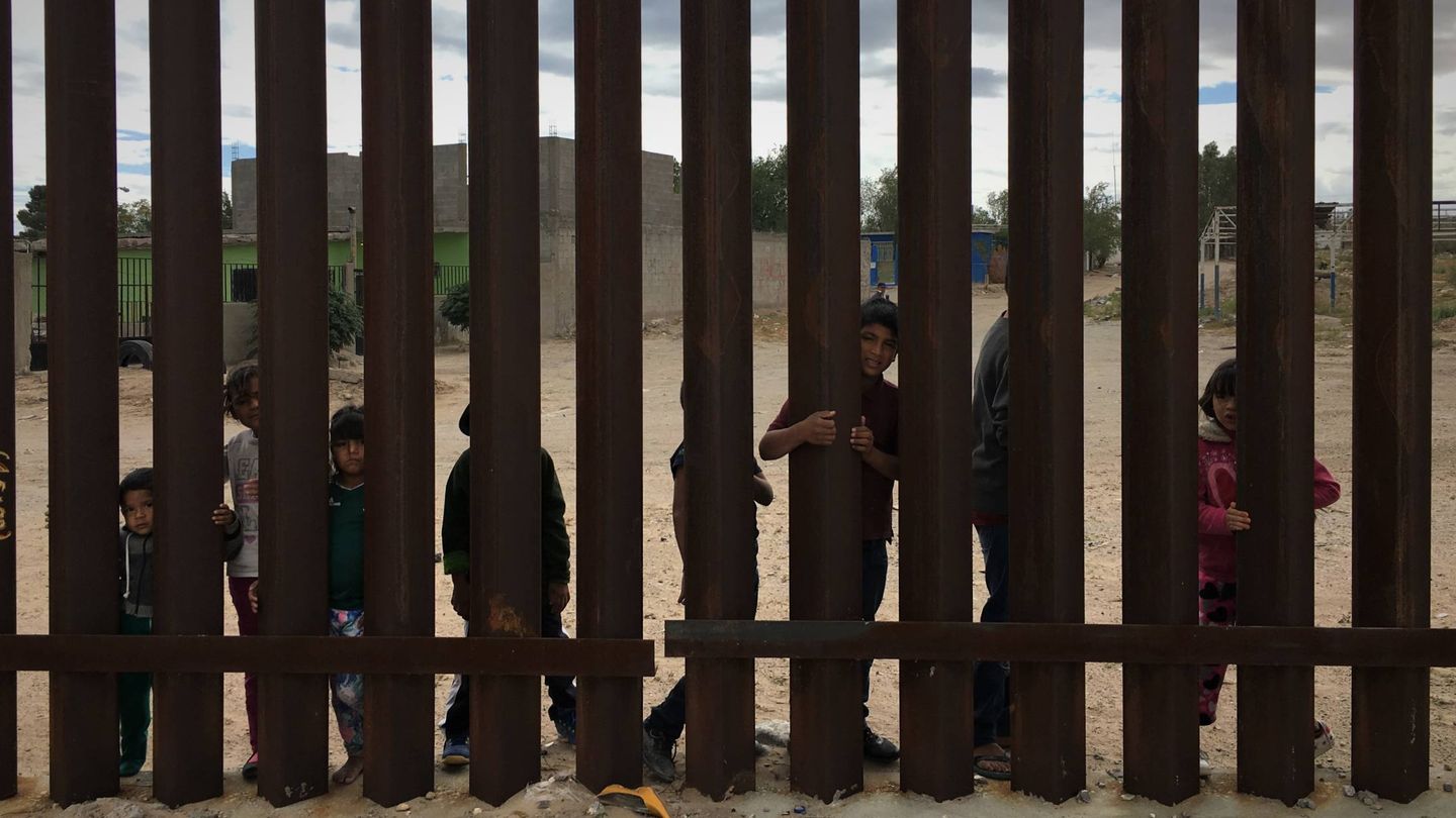 Un grupo de niños mexicanos se agarra a los barrotes de la valla fronteriza. (C. Pérez Cruz)