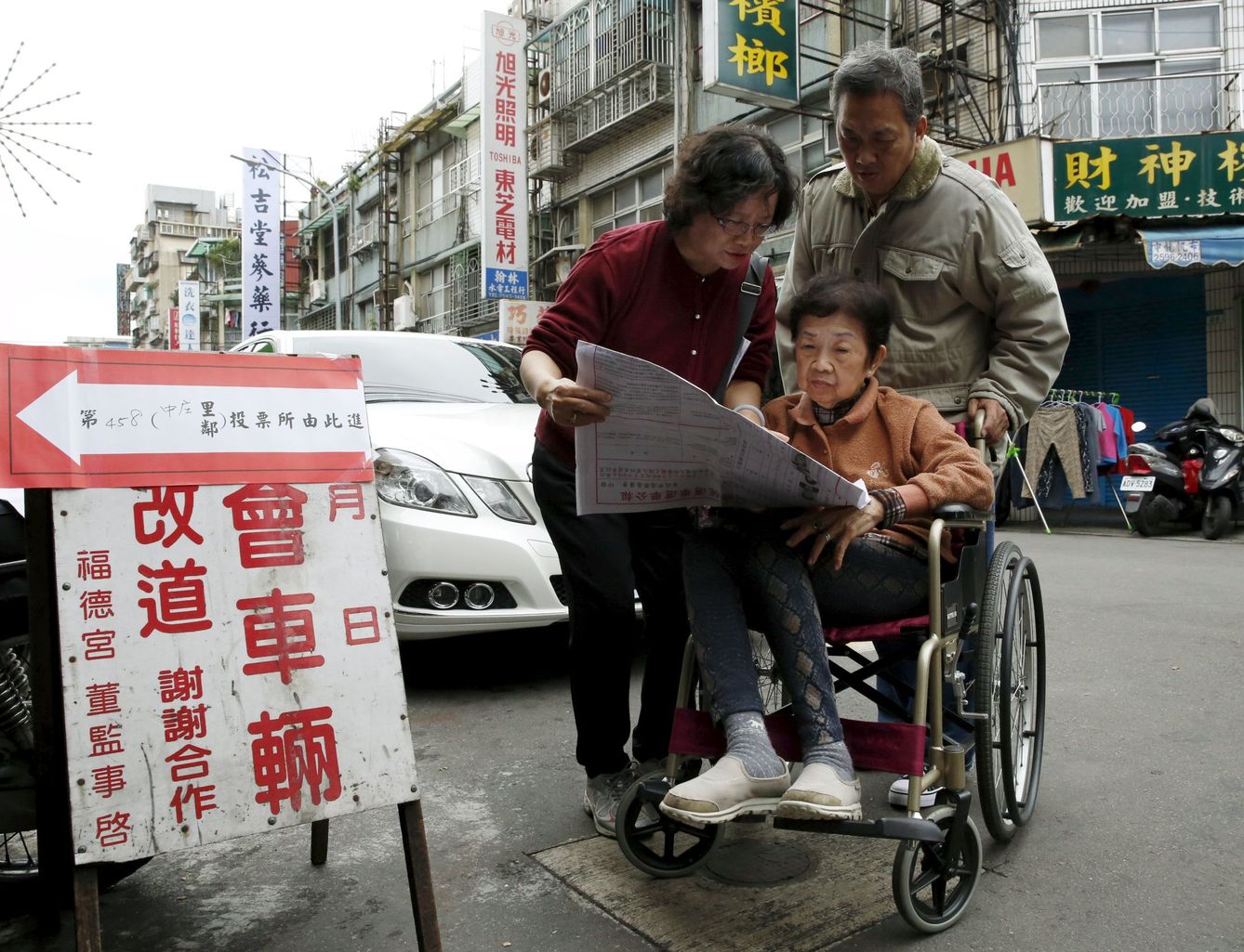 Una familia revisa las listas de candidatos antes de entrar a votar en Taipei, la capital de Taiwán, el 16 de enero de 2016. (Reuters)