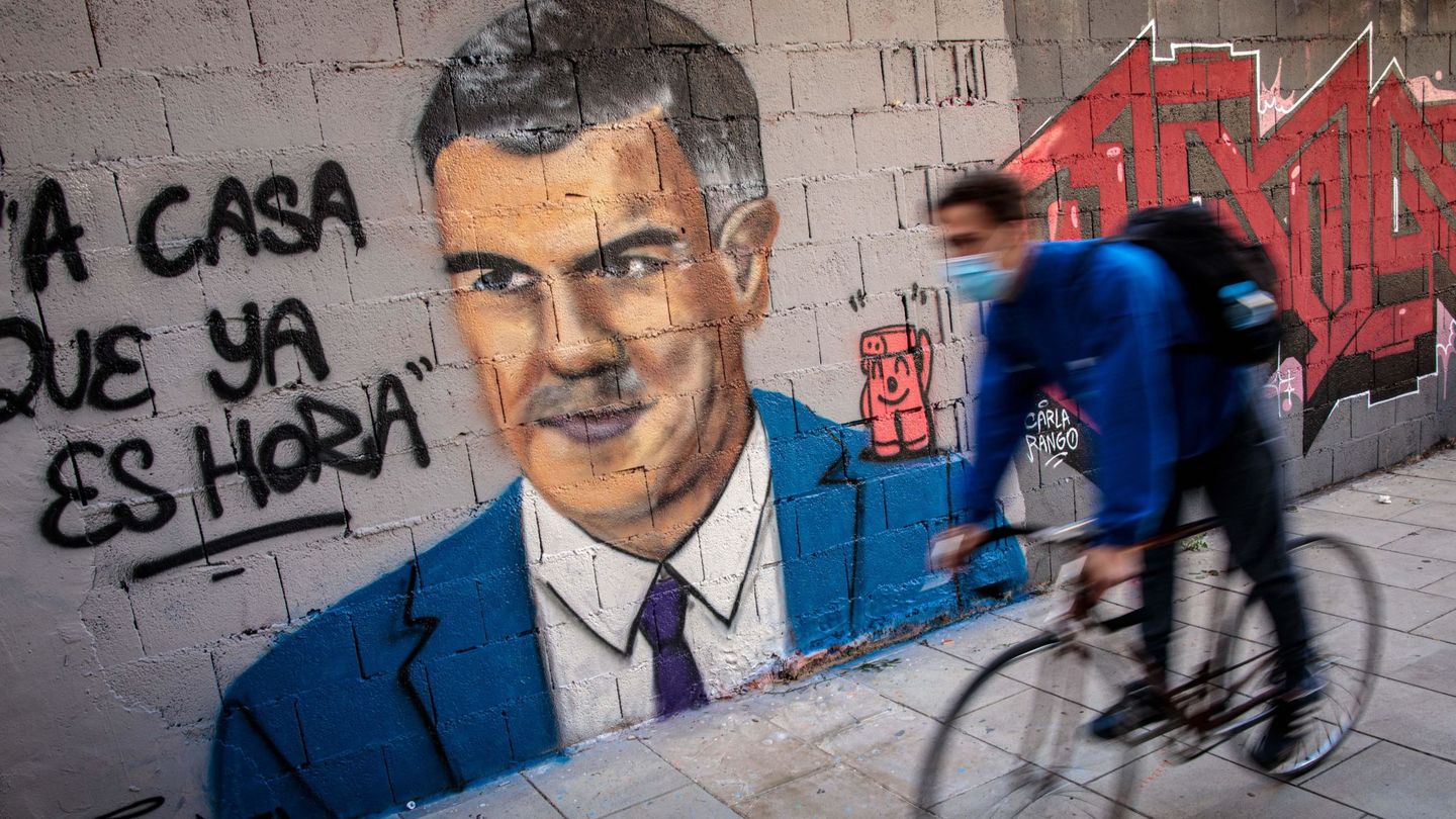 Una persona en bicicleta pasa frente a una pintura mural del artista urbano J. Warx. (EFE)