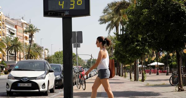 Foto: Una mujer camina junto a un termómetro que marca 43 grados. (EFE)
