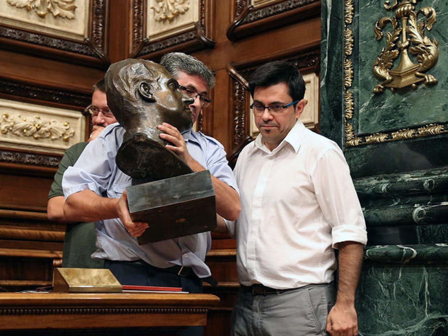Gerardo Pisarello, del Ayuntamiento de Barcelona, ayuda a retirar el busto del rey Juan Carlos I del Salón de la Reina Regente. (EFE)