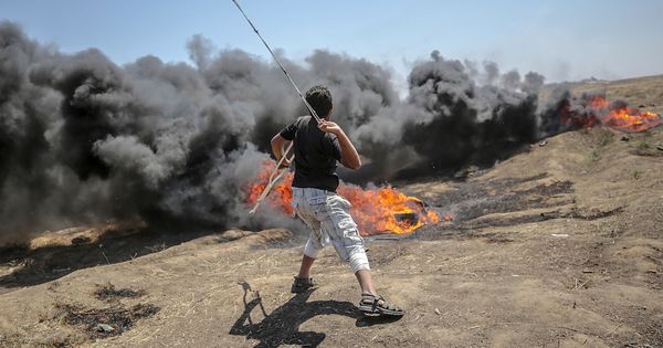 Foto: Un palestino lanza piedras hacia soldados israelíes en una protesta en la frontera de Gaza, el lunes. (EFE)
