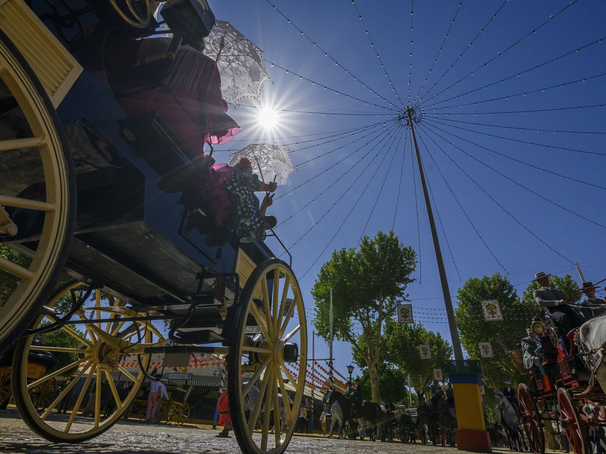 Foto: Unas mujeres pasean en coche de caballos por el Real de la Feria de Abril de Sevilla. (EFE/Raúl Caro)