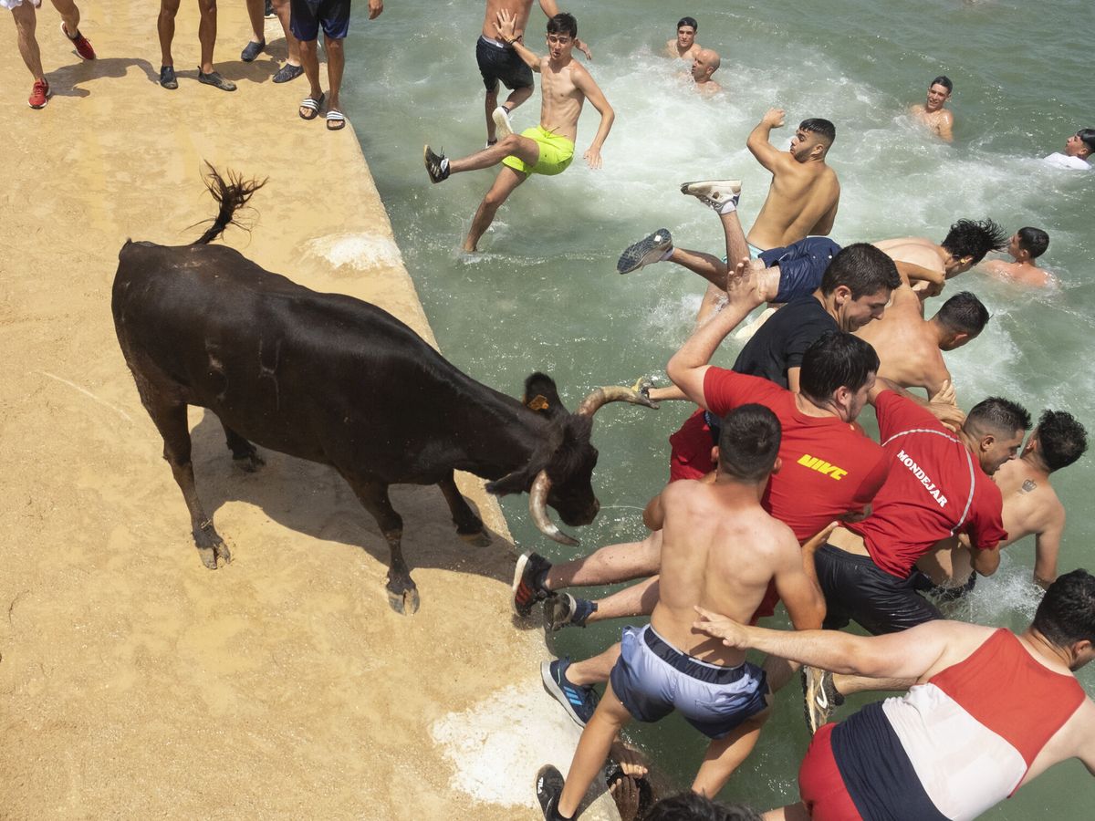 Foto: Varias personas saltan en la celebración del 'Bous a la mar' ayer domingo. (EFE/Pablo Miranzo)