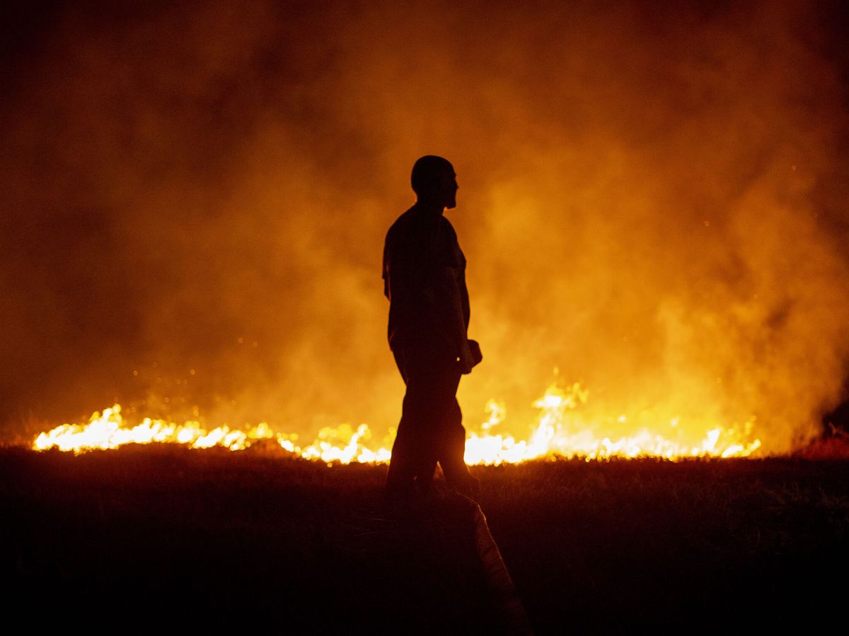 Foto: Un vecino ante las llamas del incendio en Boiro (A Coruña). (EFE/Brais Lorenzo)