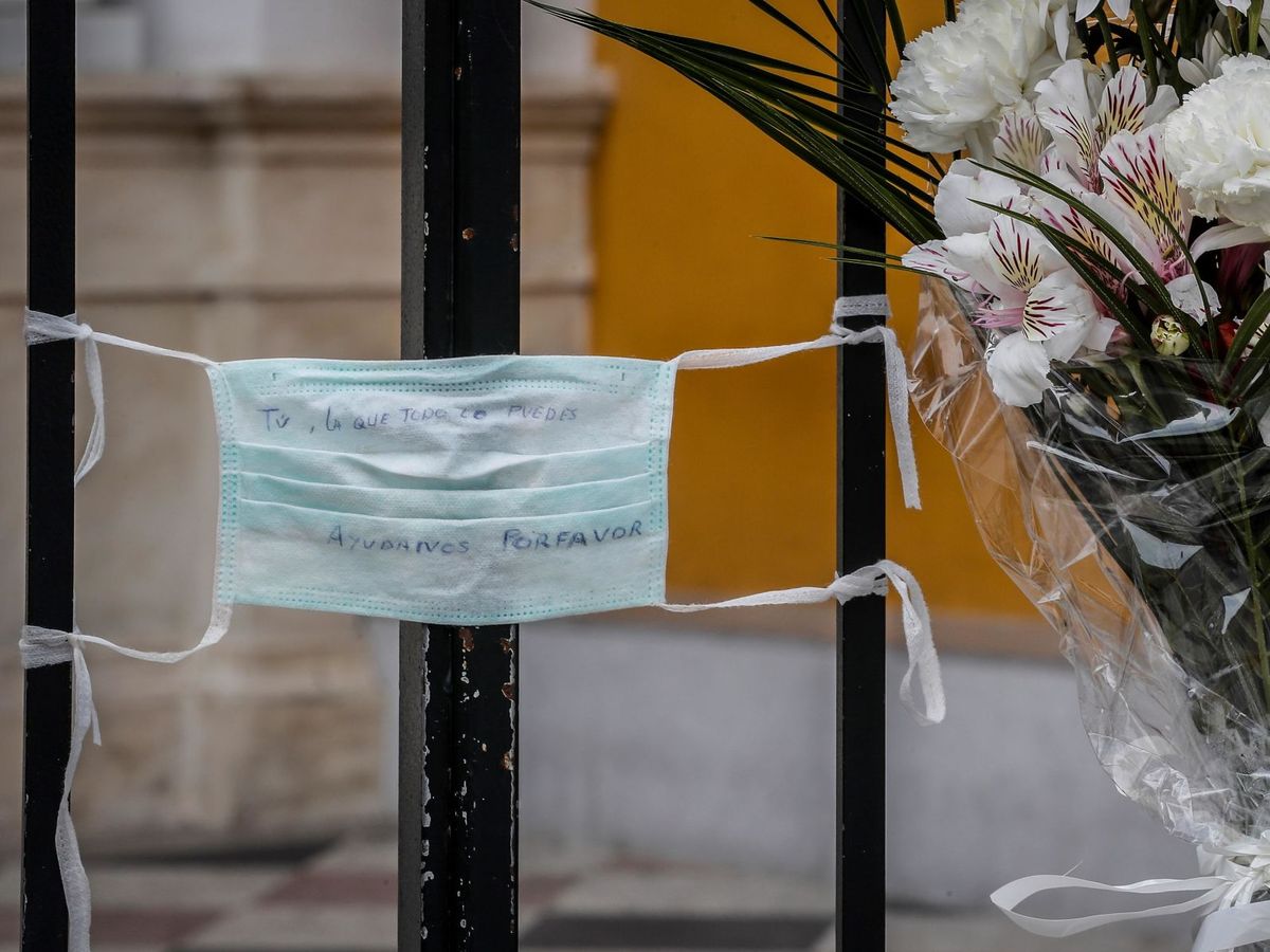 Foto: Mensajes escritos en una mascarilla colgada en la reja de la basílica de la Macarena. (EFE)