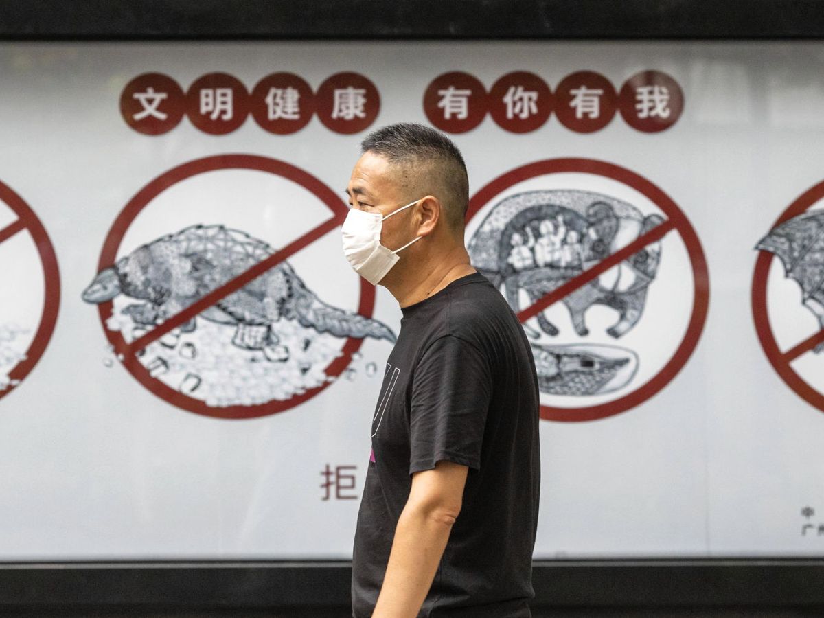 Foto: Un hombre pasa frente a un cartel contra el consumo de animales salvajes, en Guangzhou, China. (EFE)