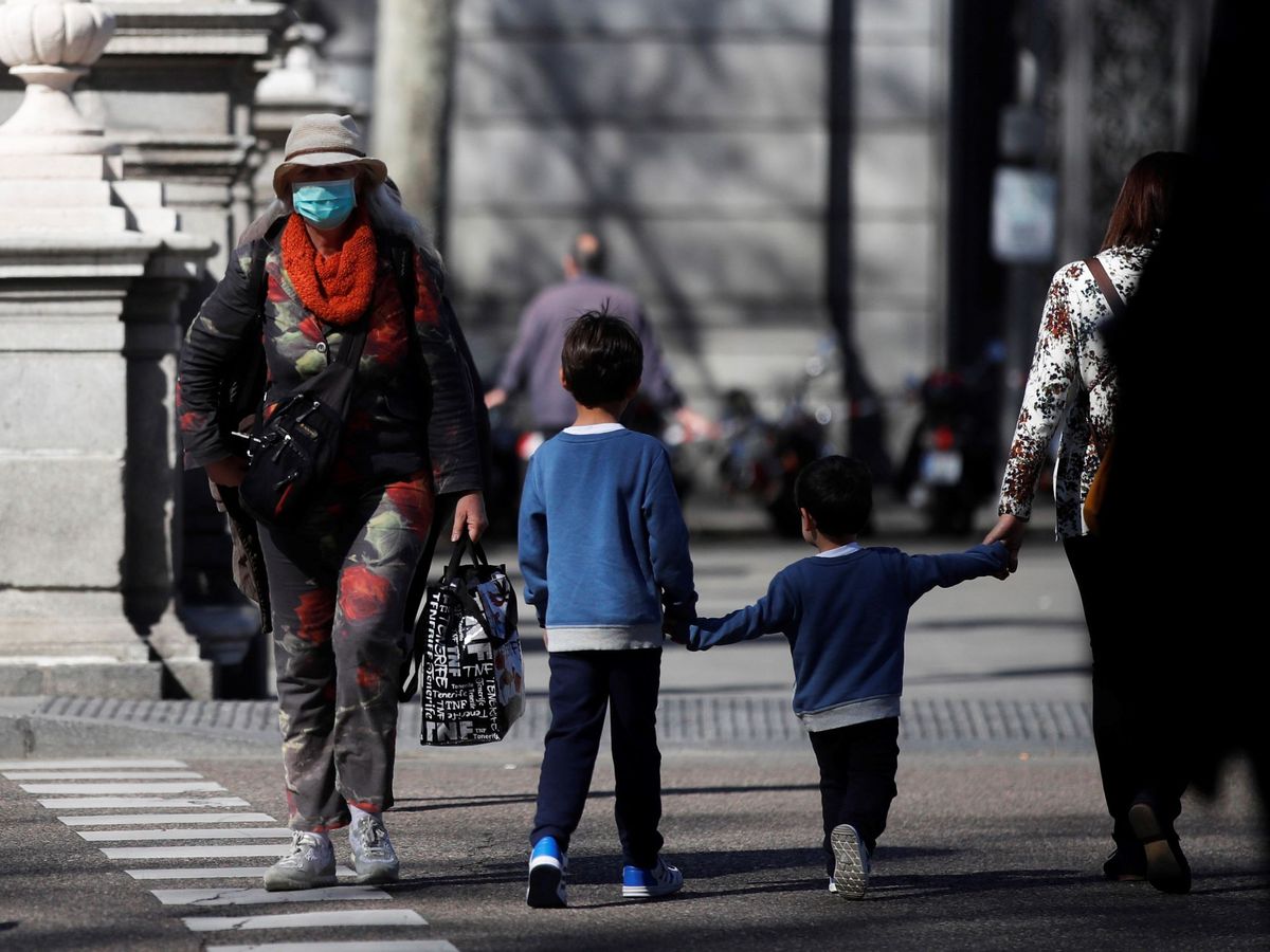 Foto: Un par de niños, sin clase, se cruzan con una persona con mascarilla en Madrid. (EFE)