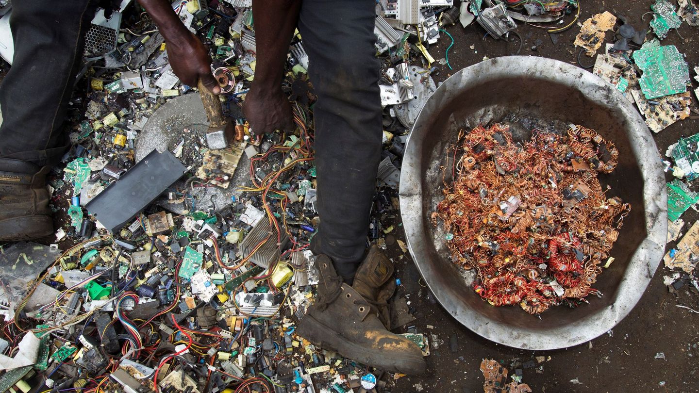 Un hombre rescata hilos de cobre de entre restos de aparatos tecnológicos en el vertedero de Agbogbloshie. (EFE)