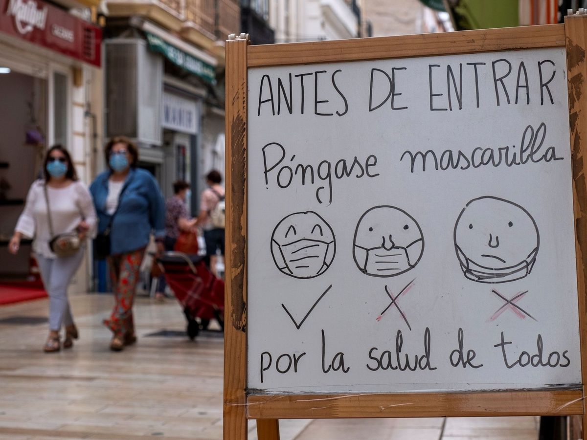Foto: Un cartel colocado a la entrada de un establecimiento de Huelva informa a los clientes de la obligatoriedad y del correcto uso de las mascarillas. (EFE)