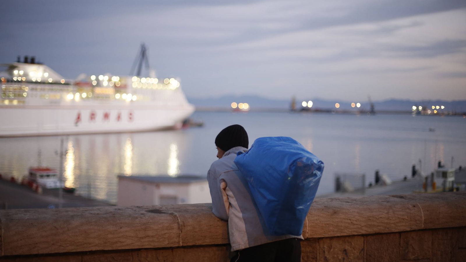 Foto: Un joven marroquí observa un barco a punto de partir del puerto de Melilla. (Reuters)
