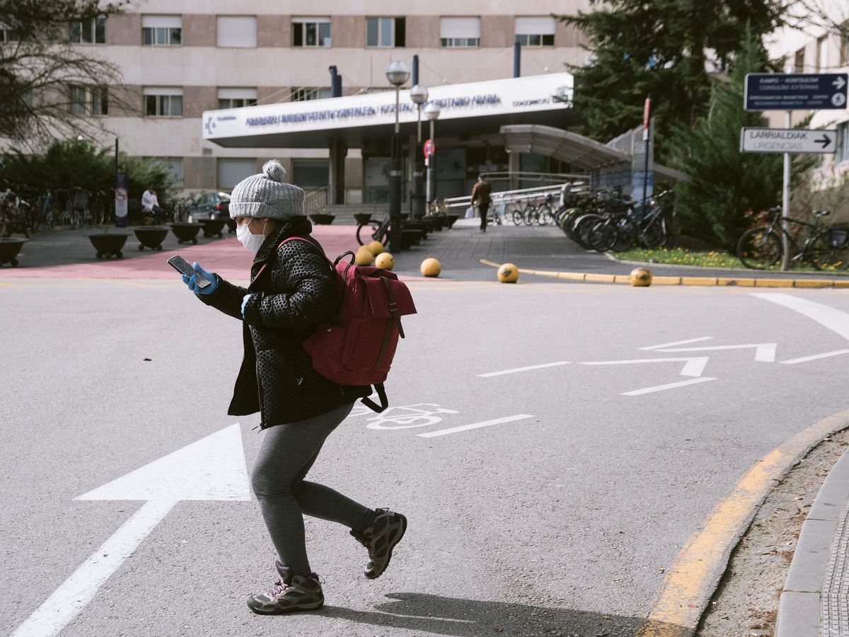 Foto: Una persona camina con mascarilla por el acceso al hospital de Txagorritxu. (EFE)