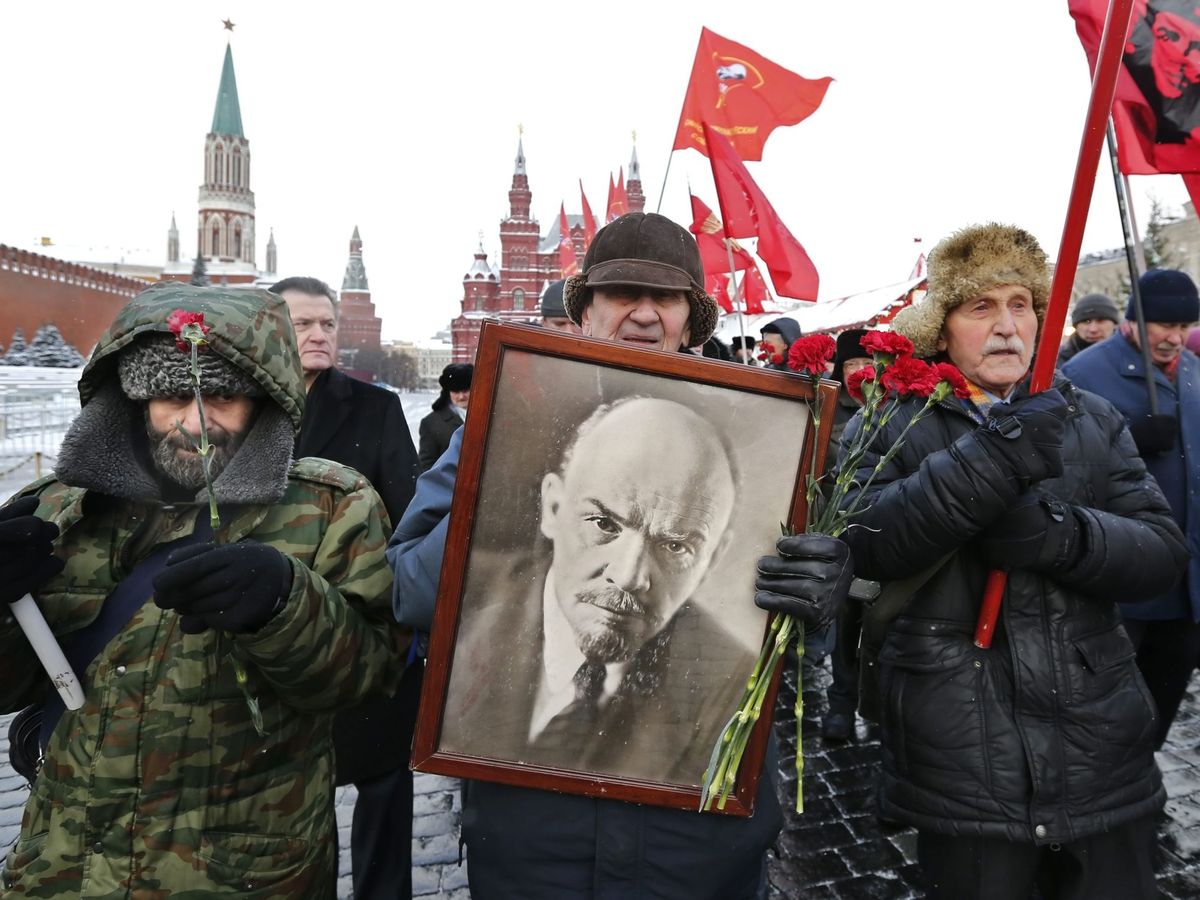 Foto: Varias personas marchan con banderas del partido comunista y una fotografía de Lenin. (EFE)