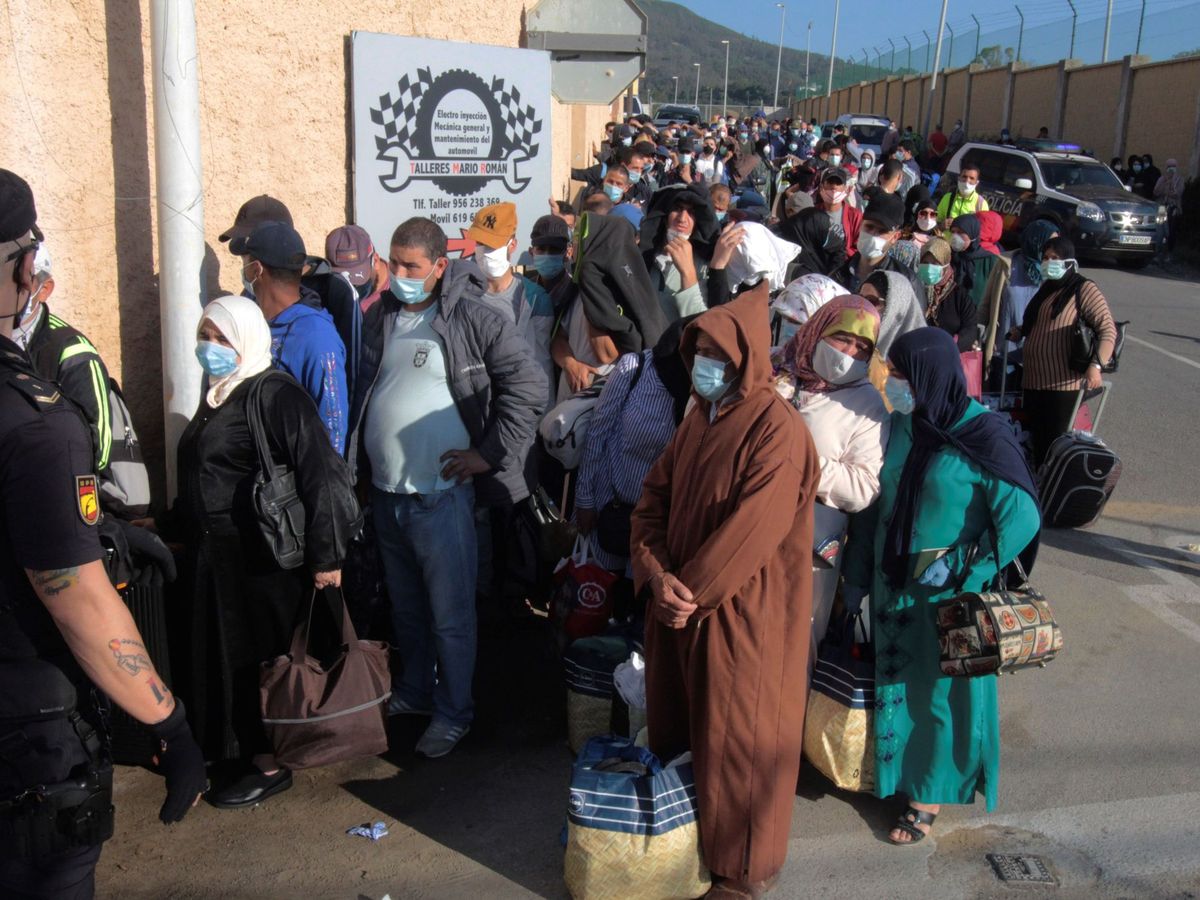 Foto: Un policía nacional vigila el proceso de repatriación de varios marroquíes en el paso fronterizo del Tarajal, en Ceuta. (EFE)