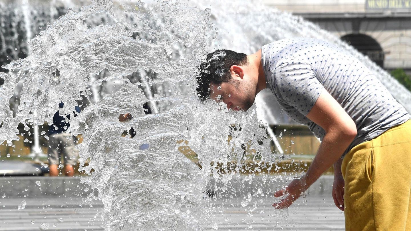 Un hombre se refresca en los chorros de agua de una fuente. (EFE)