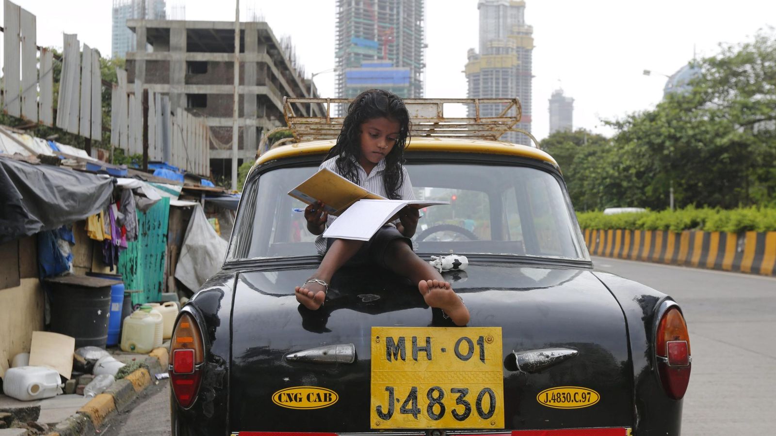 Foto: Una niña estudia en la parte trasera de un taxi en un barrio de chabolas de Mumbai, India, en agosto de 2015 (Reuters)