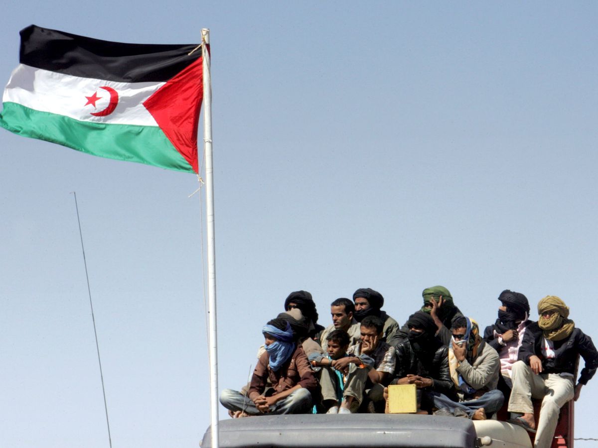 Foto: Un grupo de saharauis occidentales, junto a la bandera del territorio. (EFE)