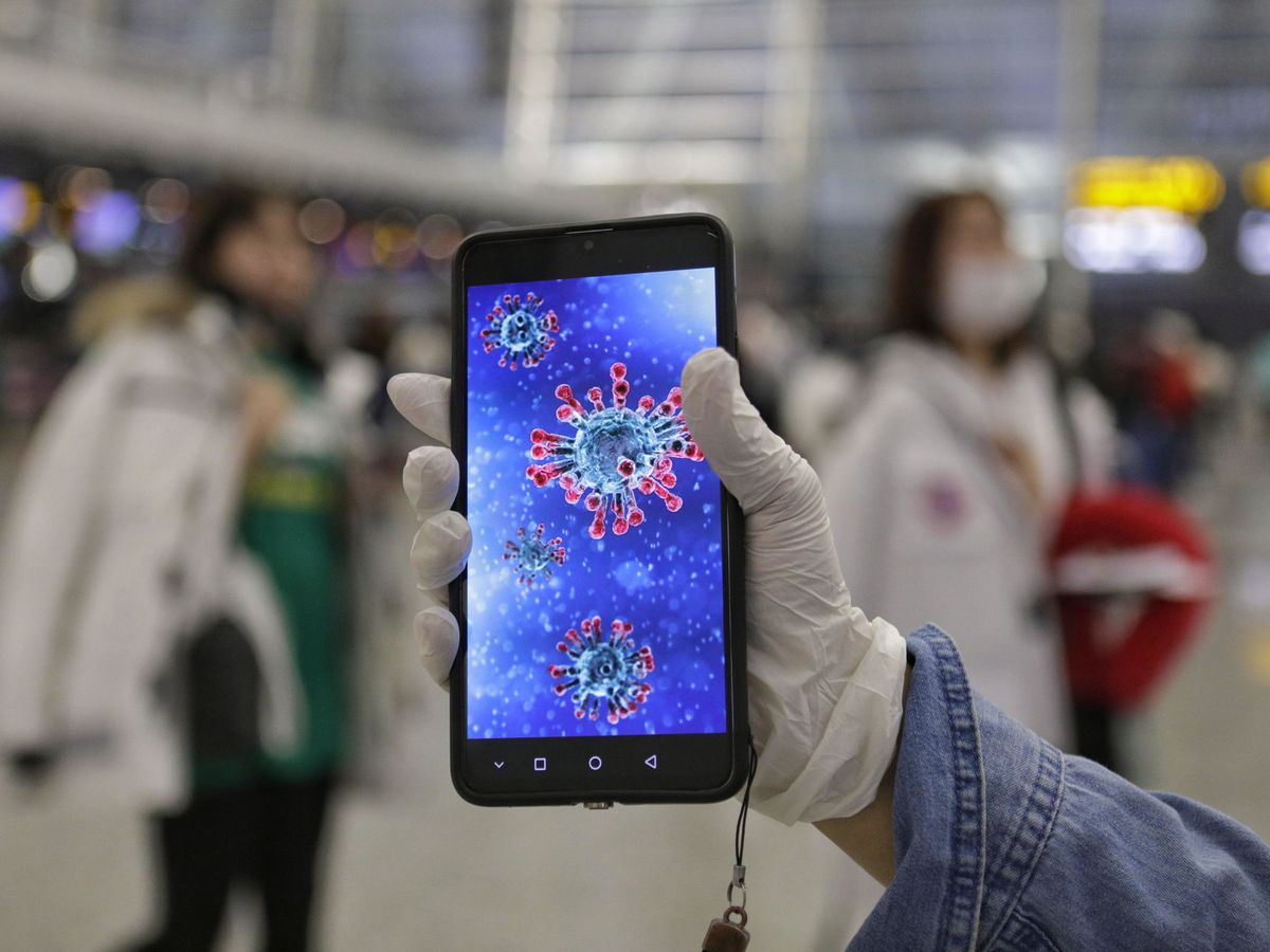 Foto: Un pasajero muestra una ilustración del coronavirus en su móvil. (EFE)