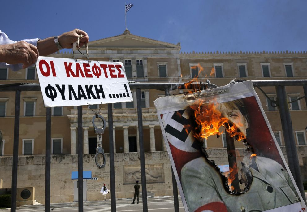 Un hombre quema un póster de la canciller Merkel ataviada con un uniforme nazi en Atenas (Reuters).
