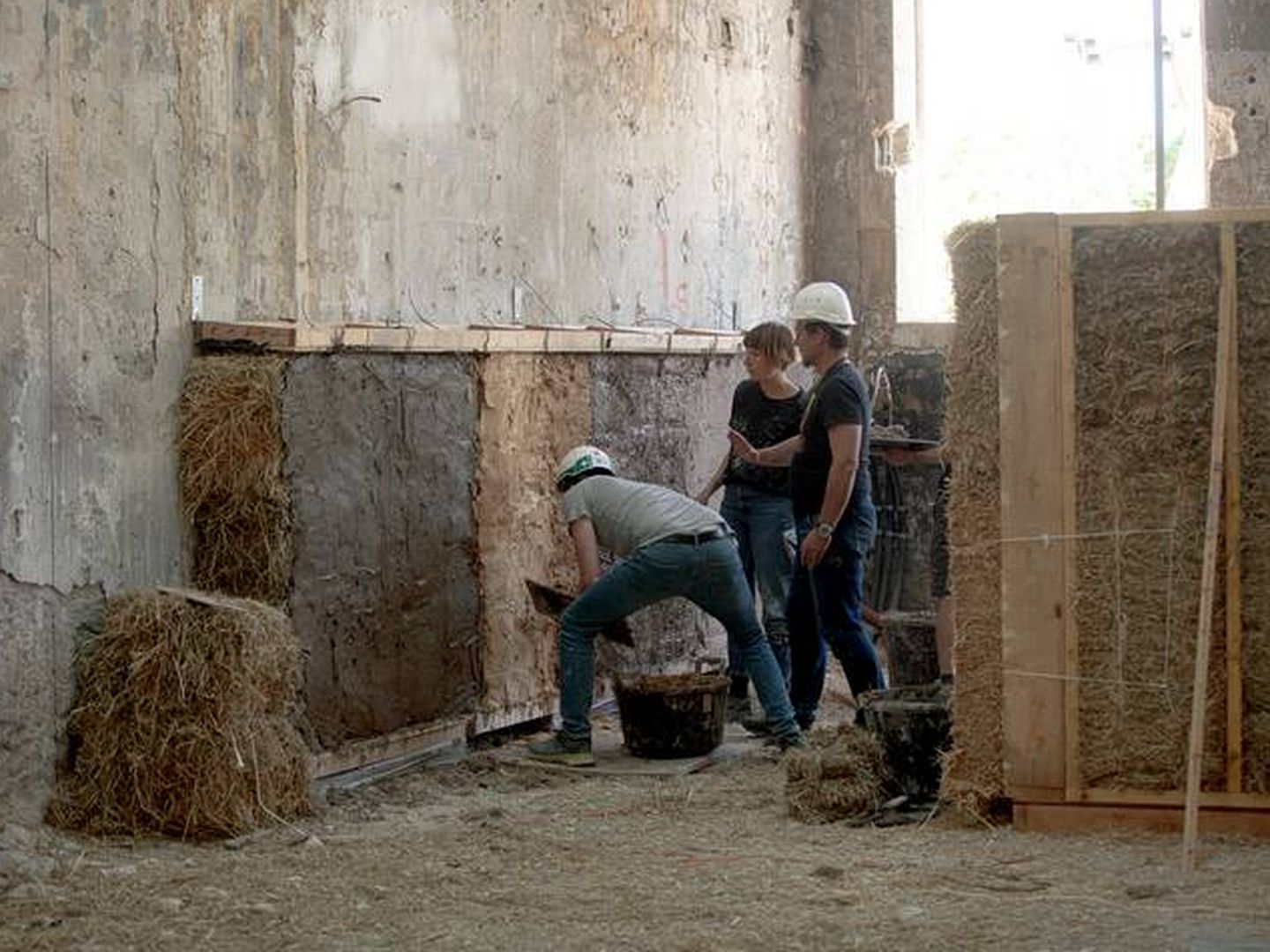 Colocación del aislamiento a base de paja de arroz en el almacén eléctrico del centro cultural Luma. © Adrian Deweerdt