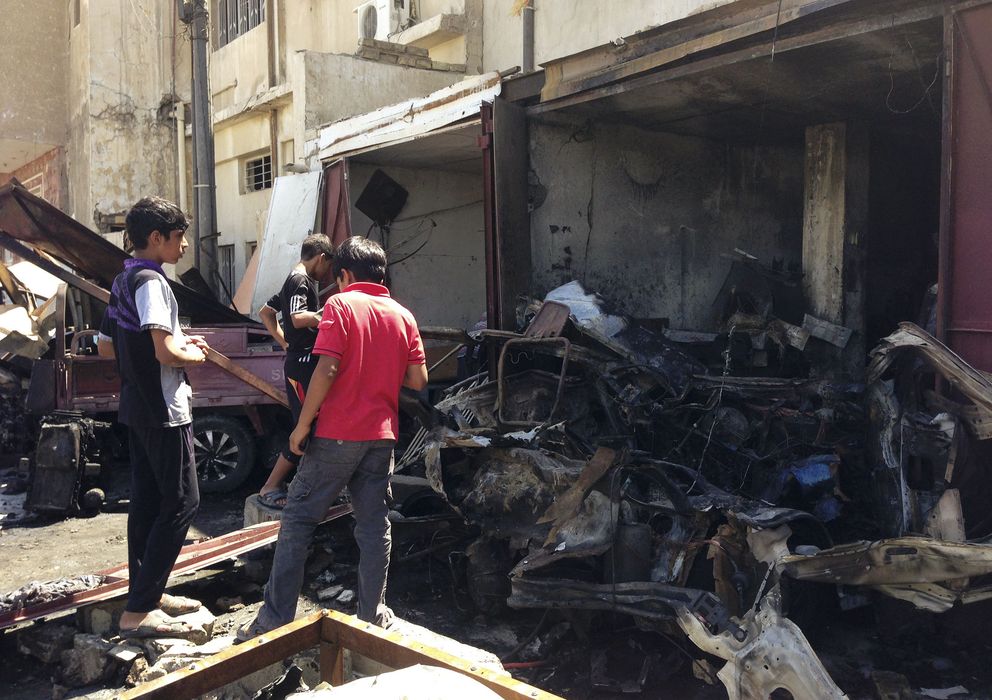 Foto: Unos jóvenes observan los restos de un coche bomba en Bagdad el pasado 29 de julio (Reuters).