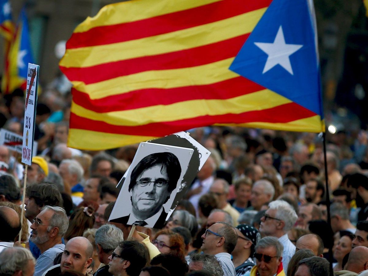 Foto: Varios manifestantes portan una estelada junto a una fotografía del expresidente de la Generalitat Carles Puigdemont en el segundo aniversario del 1-O. (EFE)