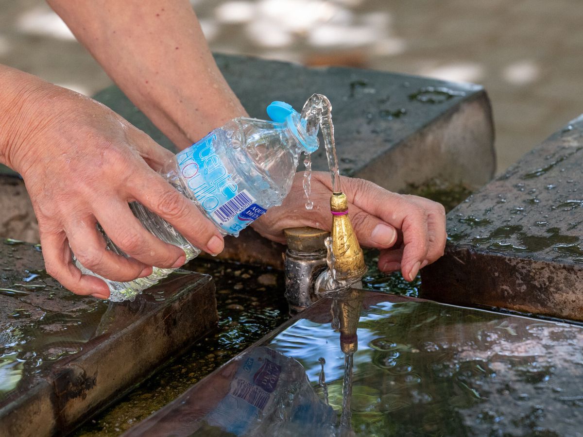 Foto: Una mujer llena una botella de agua para refrescarse. (EFE/Raquel Manzanares)