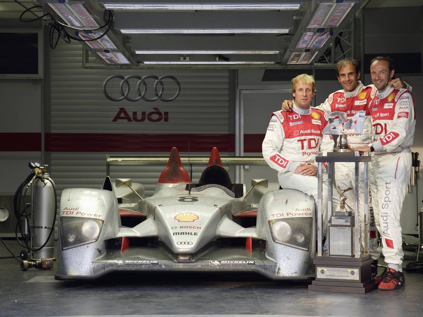 El R10 TDI de motor diésel ganador en Le Mans en 2006, junto a sus tres pilotos: Frank Biela, Emmanuele Pirro y Marco Werner.