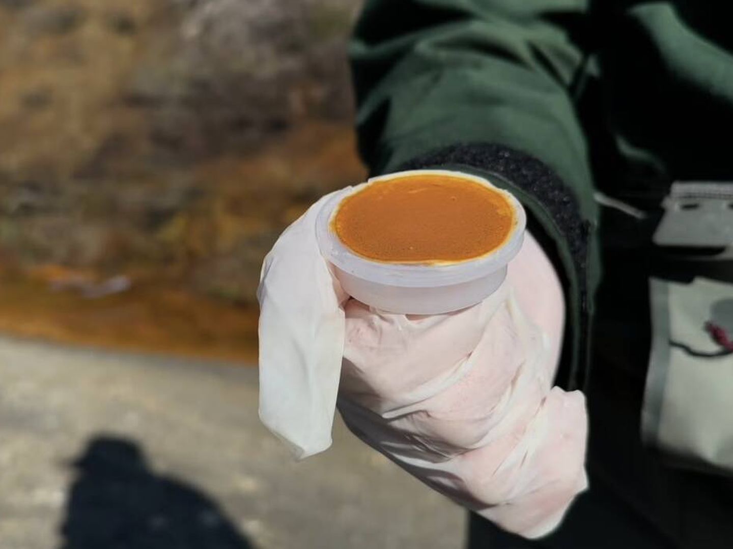 Evinger sostiene un filtro de color naranja brillante recogido de una filtración afectada por el drenaje ácido de rocas en medio del permafrost en deshielo (Taylor Evinger/UC Davis)