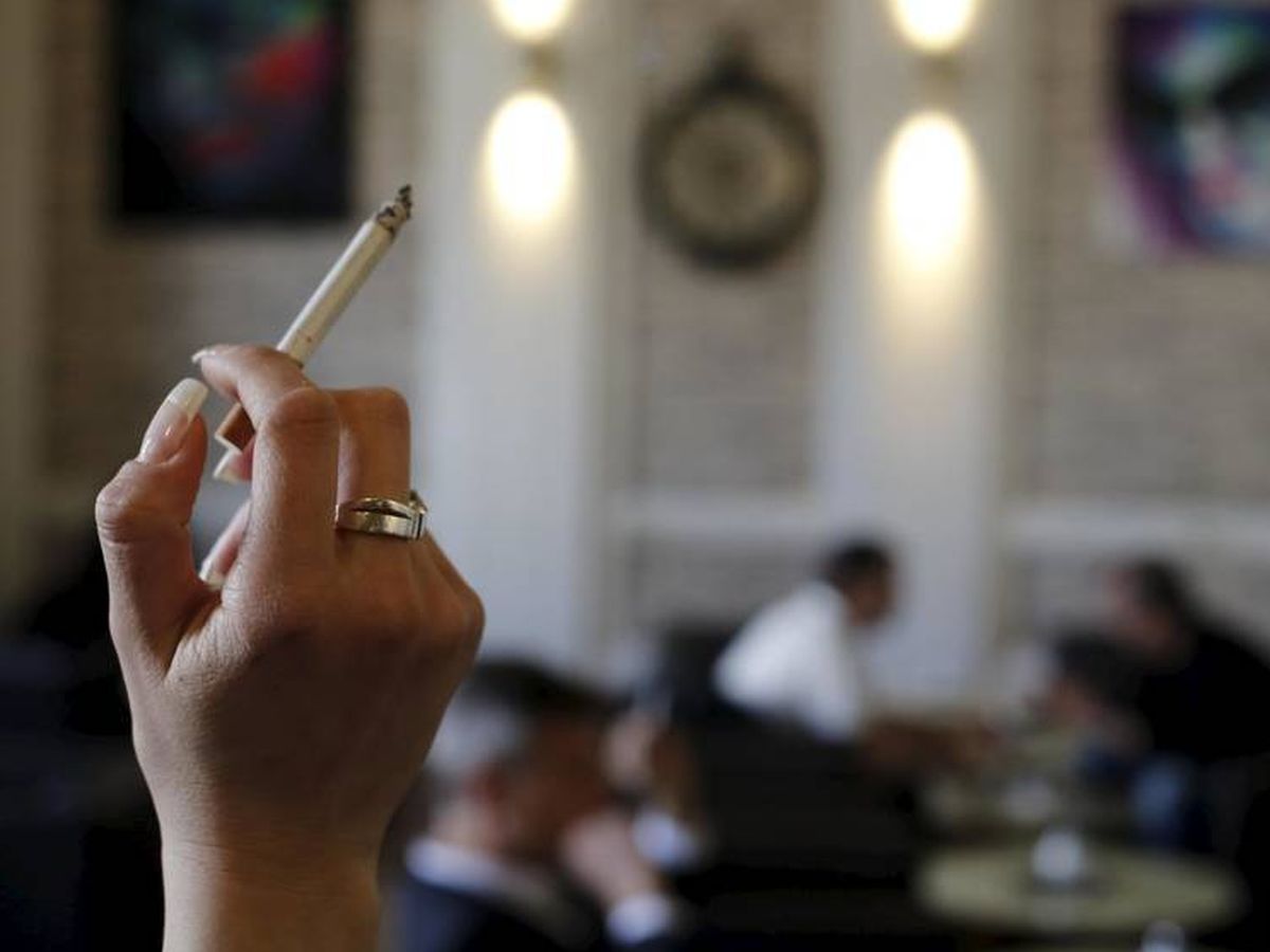 Foto: Una mujer sostiene un cigarrillo en un café. (Reuters)
