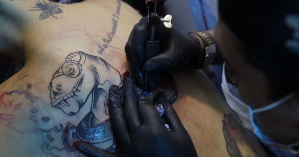 Foto: Tatuador trabajando en su diseño| EFE