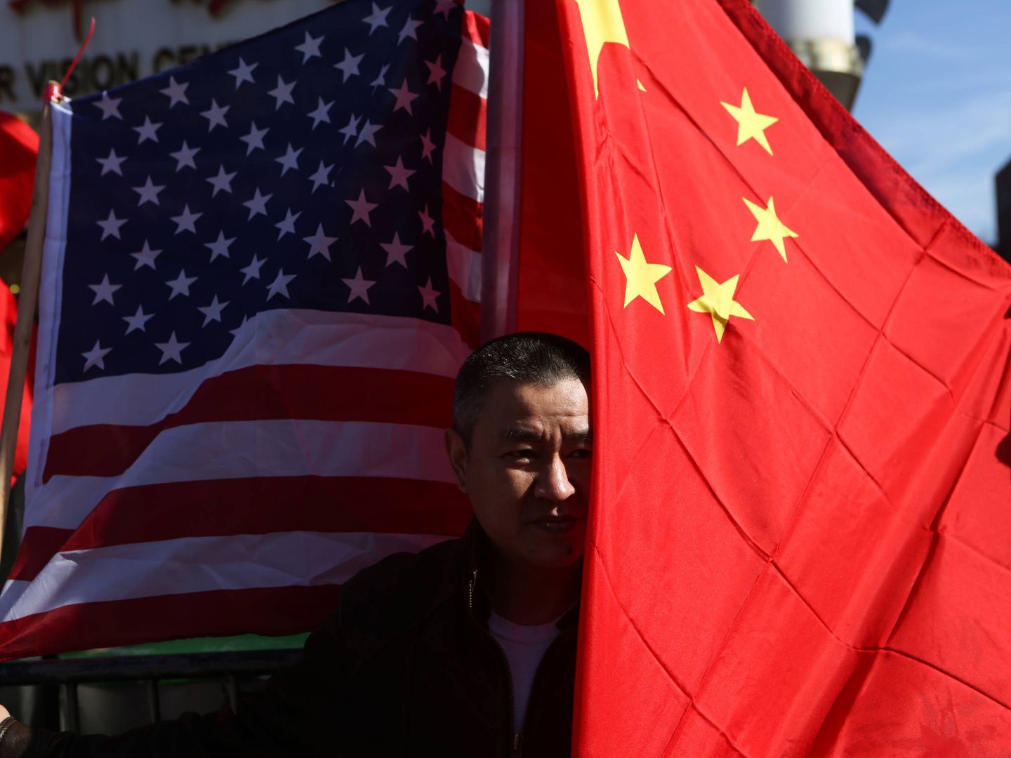 Un hombre posa con una bandera estadounidense y otra china en Queens, Nueva York. (Reuters)