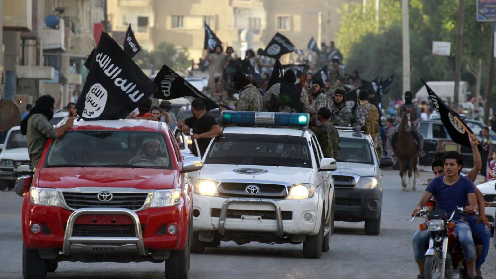 Foto: Militantes del ISIS ondean banderas del grupo durante un desfile militar en Raqqa, Siria. (Reuters)