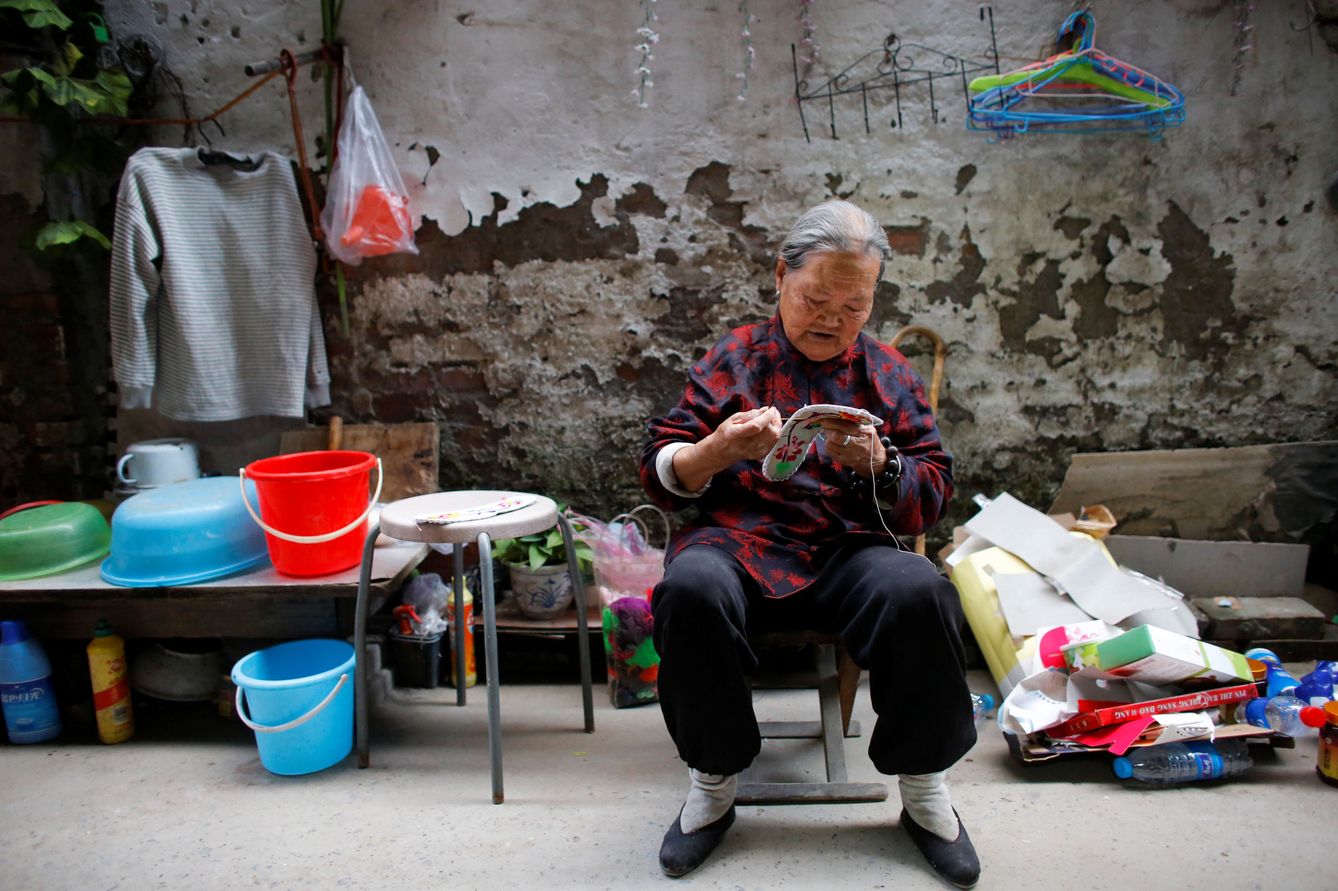 La señora Zhong, una inmigrante rural, remienda zapatos en el patio de su casa en el extrarradio de Pekín, el 1 de octubre de 2017. (Reuters)