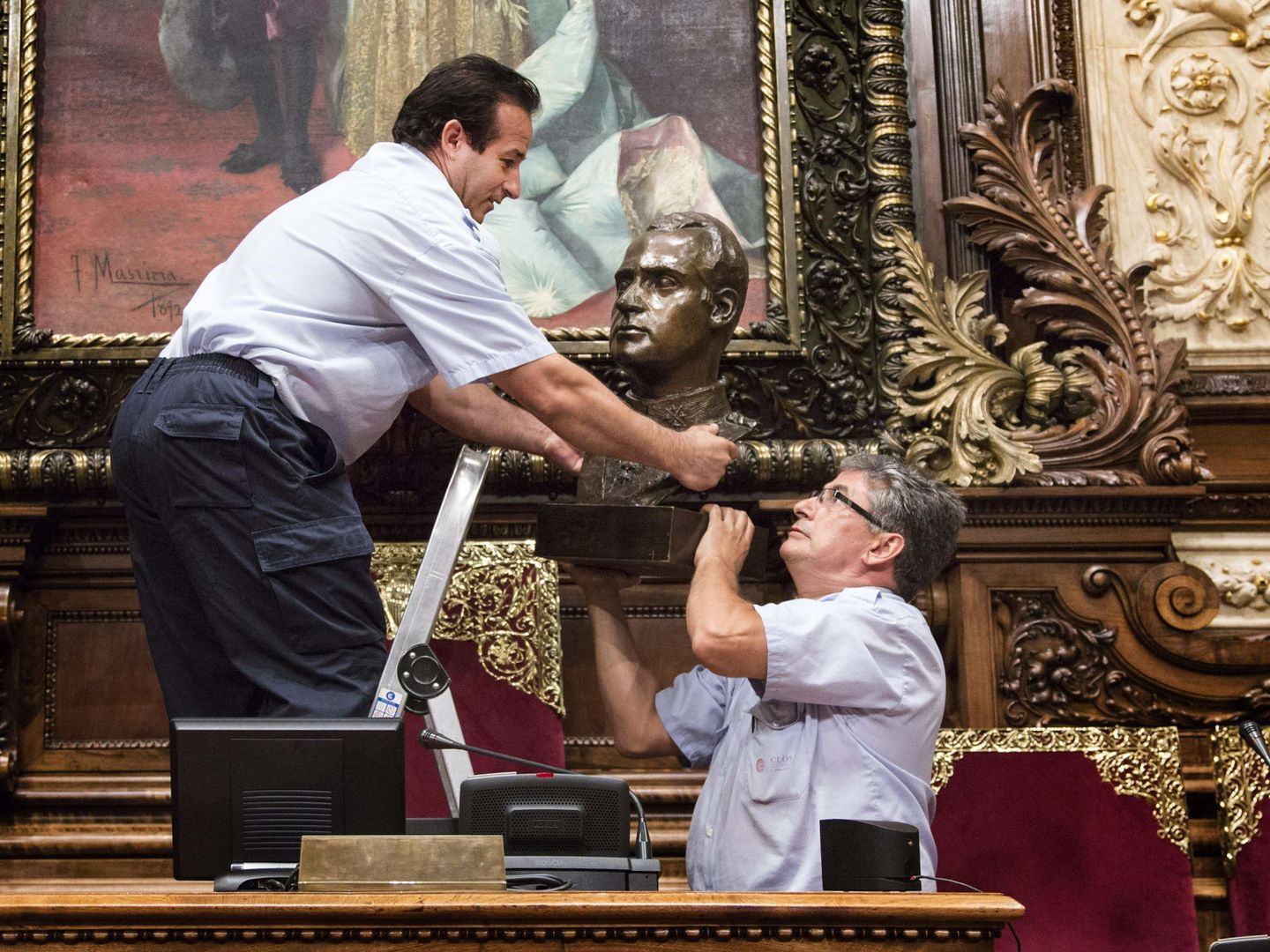 Dos operarios municipales retiran el busto del Rey Juan Carlos I. (EFE)