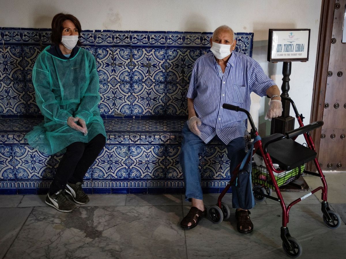 Foto: Un residente del Hospital de la Caridad de Sevilla junto a un familiar, el pasado junio. (EFE)