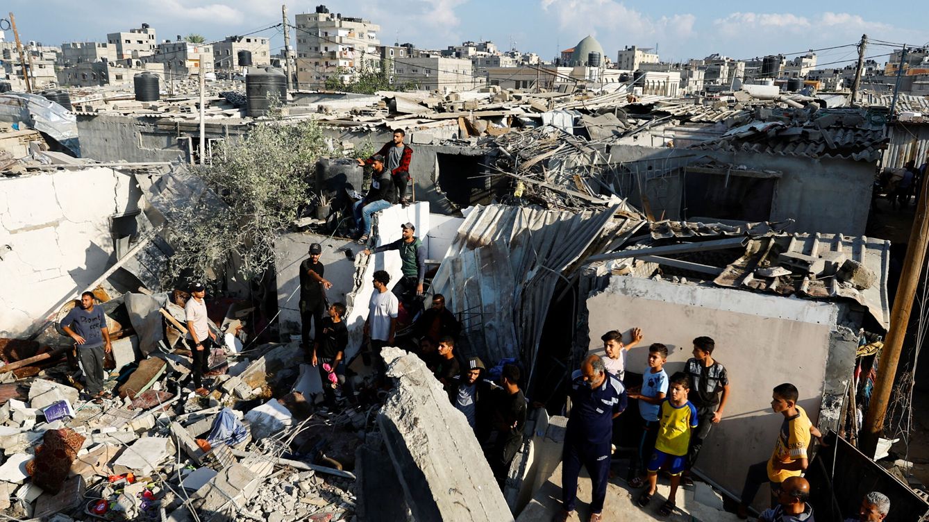 Foto: Un grupo de palestinos sobre casas destruidas por los ataques. (Reuters/Ibraheem Abu Mustafa)