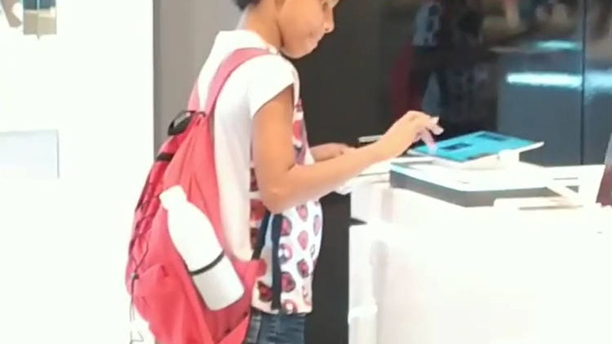 Graban a un niño que va a una tienda para poder hacer sus deberes con una tablet