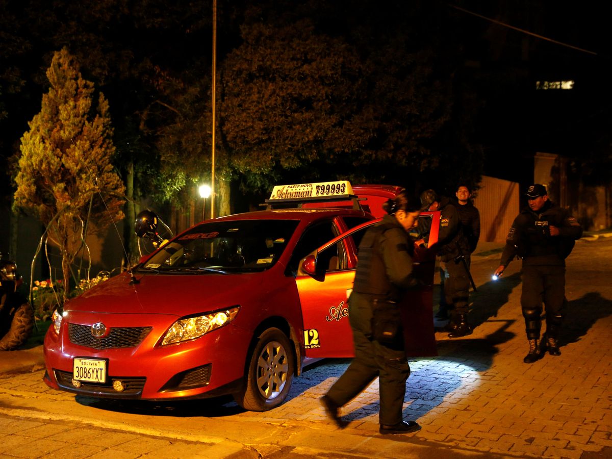 Foto: Oficiales de policía inspeccionan un vehículo en la entrada de la residencia del embajador de México en Bolivia. (Reuters)