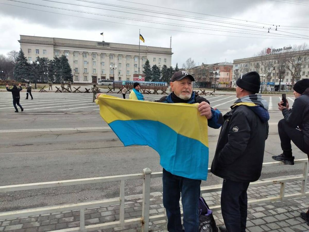 Foto: Mario García, con una bandera ucraniana ante soldados rusos en Jersón. 