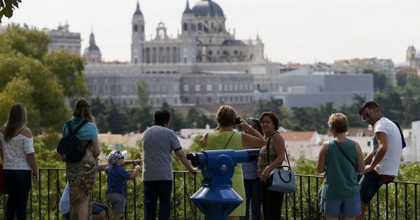 Foto: Varias personas observan las vistas del Palacio Real y la catedral de la Almudena desde los jardines del templo de Debod, en Madrid. (EFE)