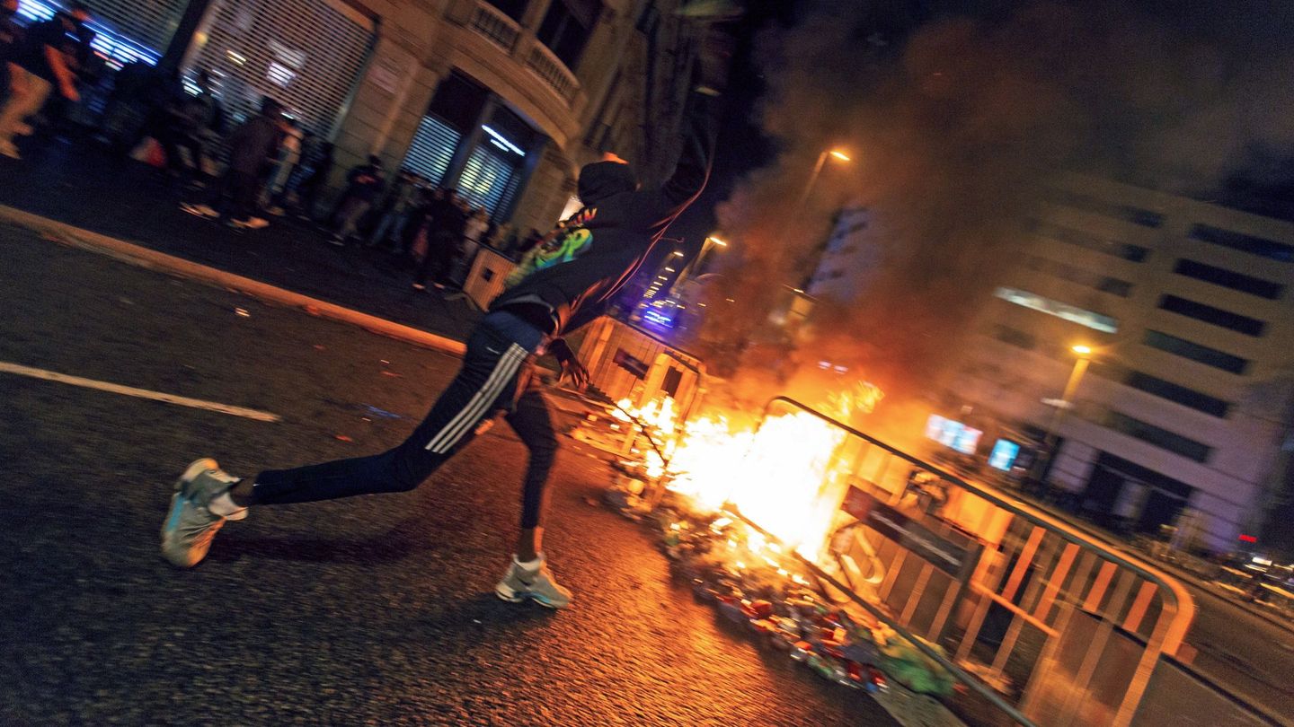 Un manifestante lanza piedras contra la Policía desde una barricada. (EFE)
