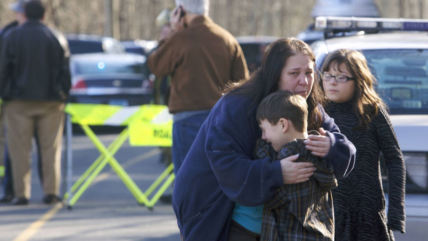 Dos niños supervivientes de la matanza de la escuela de Sandy Hook son abrazados por un pariente. (Reuters)