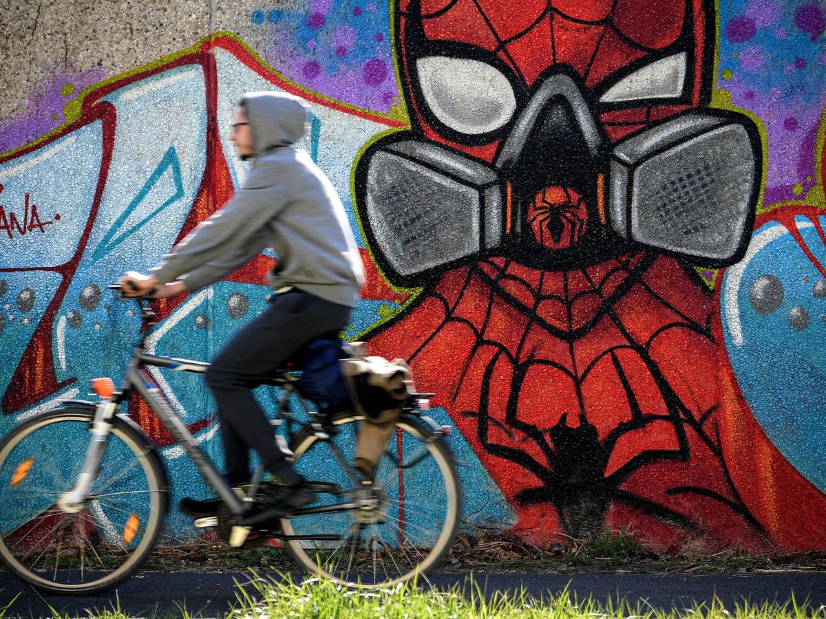 Foto: Un joven pasa en bicicleta delante de un grafiti en Hamm, Alemania. (EFE)