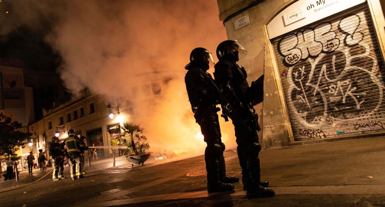 Dos agentes de los Mossos durante los disturbios en Barcelona. (EFE)