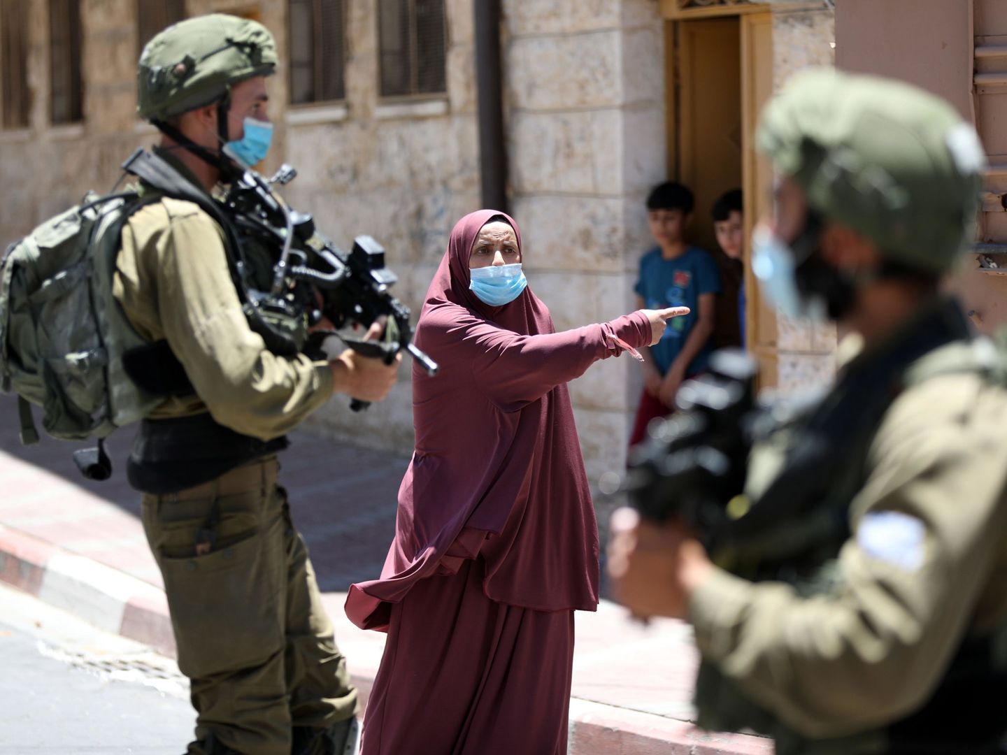 Una mujer palestina discute con soldados israelíes en Hebrón, después de que los militares detuvieran a su hijo en un control rutinario. (EFE)