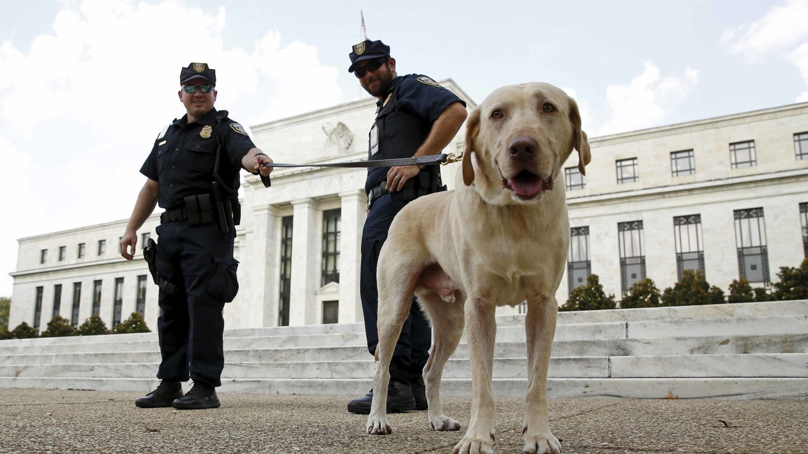 Foto: Dos policías vigilan con su perro la entrada de la sede de la Fed en Washington./REUTERS