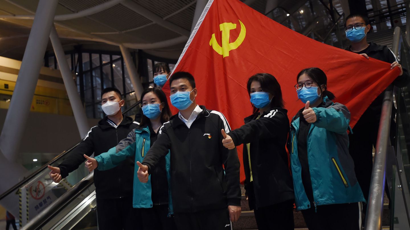 Varios médicos chinos posan con una bandera comunista detrás. (Reuters)