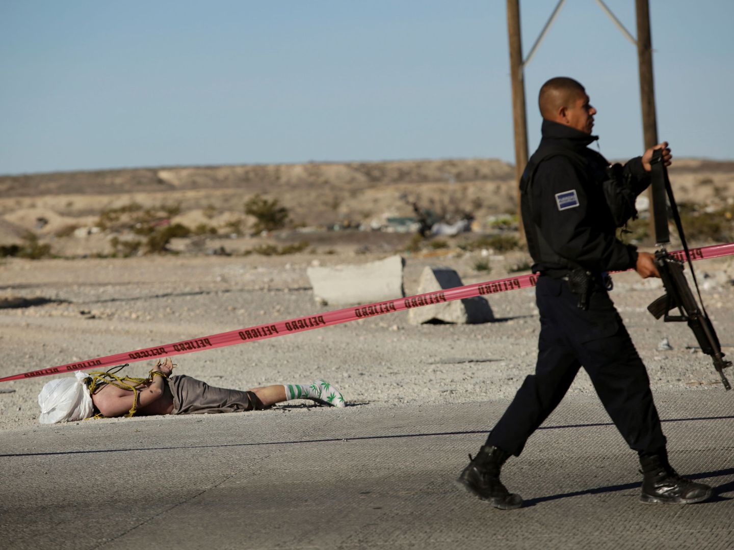 Un policía pasa ante un cadáver en las afueras de Ciudad Juárez. (Reuters) 